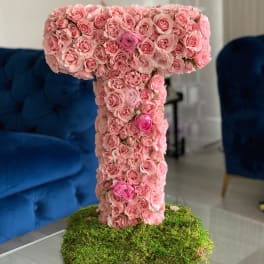 Pink rose-covered letter T on a moss base