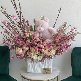 Pink teddy bear in a large arrangement of pink and cream roses