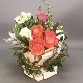 Bouquet of orange and white roses in a paper-wrapped container