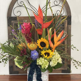 Tropical floral arrangement with sunflowers and orange heliconia in a decorative box