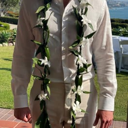 Man wearing a white shirt with two white floral leis