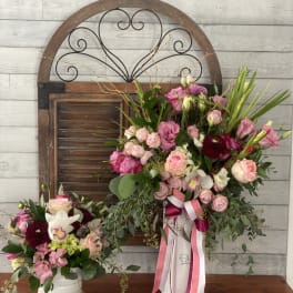Two pink floral arrangements in white vases with ribbon accents