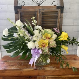 Mixed floral arrangement in a glass vase with white, yellow, and lavender blooms