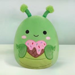 Green plush character with antennae holding a pink sprinkled heart-shaped treat.