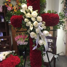 Large red floral cross with white roses and calla lilies on an easel