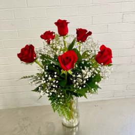 Red roses arranged in a clear glass vase with white filler flowers