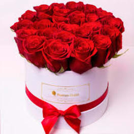 Round box of red roses with a red ribbon bow