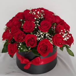 Red roses arranged in a black round box with a red ribbon