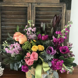 Mixed bouquet in a basket with roses, tulips, and purple blooms