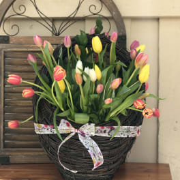 Basket arrangement of pink, yellow, and white tulips with a ribbon