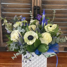 Bouquet of cream and purple flowers in a white textured vase