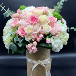 Pink and white rose bouquet in a brown paper wrap with a ribbon