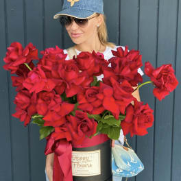 Woman holding a large box of red roses with a ribbon