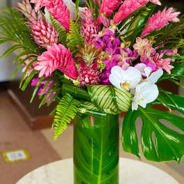 Pink tropical flowers arranged in a green vase with white orchids