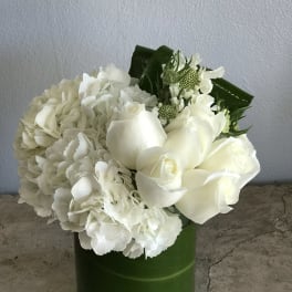 White roses and hydrangeas arranged in a green vase