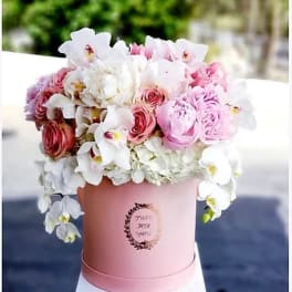 Pink and white floral arrangement in a round pink box