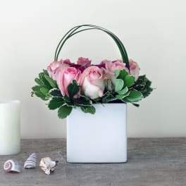 Pink roses in a white square container with a green handle