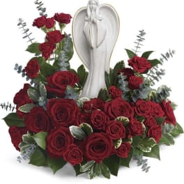 Red rose arrangement around a white angel figurine