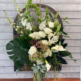Tall white floral arrangement in a glass vase with a sage ribbon