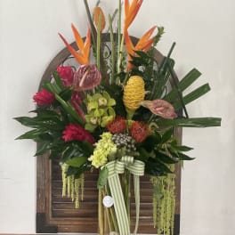 Tropical flower arrangement in a glass vase with orange bird-of-paradise and pink blooms