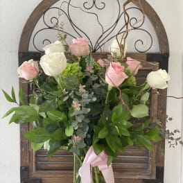 Pink and white roses in a glass vase with a pink ribbon