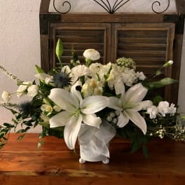 White lily and mixed white floral arrangement in a ceramic vase