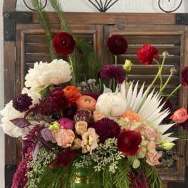 Mixed bouquet in a green-and-gold vase with red, white, and purple flowers