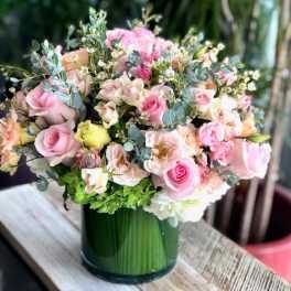 Pink and peach roses arranged in a green glass vase