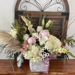 Mixed bouquet in a striped square container with pink ribbon