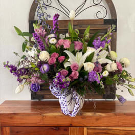 Mixed bouquet with white lilies, pink roses, and purple flowers in a ribbon-tied vase