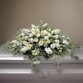 White floral casket spray with roses and greenery