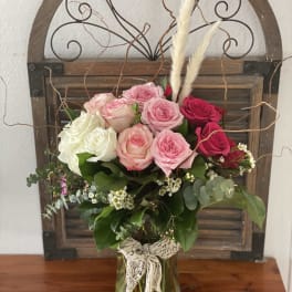 Bouquet of pink, white, and red roses in a glass vase