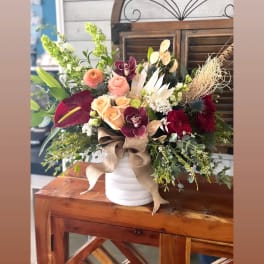 Mixed bouquet in a white vase with roses, orchids, and calla lilies