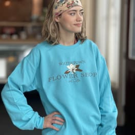 Woman wearing a turquoise flower shop sweatshirt and floral headband