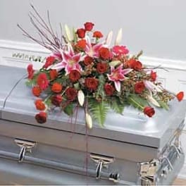Red roses and pink lilies arranged as a casket spray on a silver casket