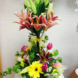 Tall mixed bouquet with lilies, tulips, and a yellow gerbera daisy in a vase