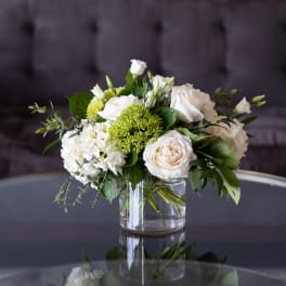 White floral arrangement in a clear glass vase on a table