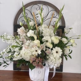 White floral arrangement in a white container with ribbon