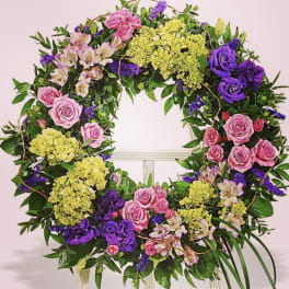 Circular floral wreath with pink roses, purple blooms, and yellow hydrangeas