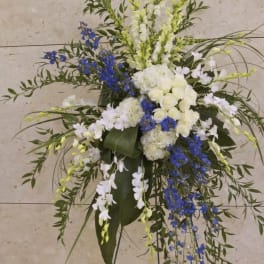Tall white and blue floral standing spray on a black easel