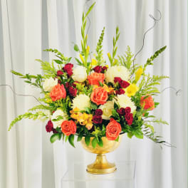 Mixed bouquet of roses and white blooms in a gold pedestal vase