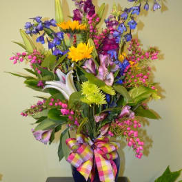 Colorful mixed flower arrangement in a blue vase with a plaid ribbon