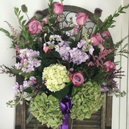 Pink roses and lavender flowers in a tall vase with green hydrangeas