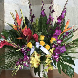 Tropical flower arrangement with orchids and roses in a white vase