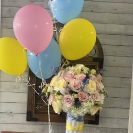 Pastel rose bouquet with pink, yellow, and blue balloons