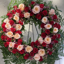 Heart-shaped wreath of red and blush roses on a stand