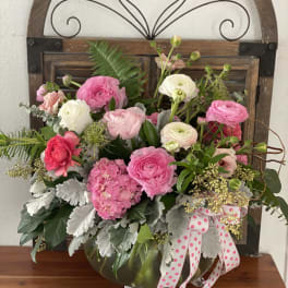 Pink and white flower arrangement in a glass vase with a polka-dot ribbon