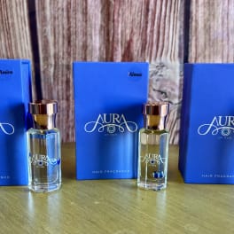 Three blue hair fragrance boxes with matching glass bottles on a wooden surface