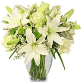 White lilies and roses arranged in a clear glass vase