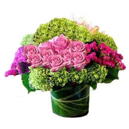 Pink roses in a green glass vase with bright mixed filler flowers